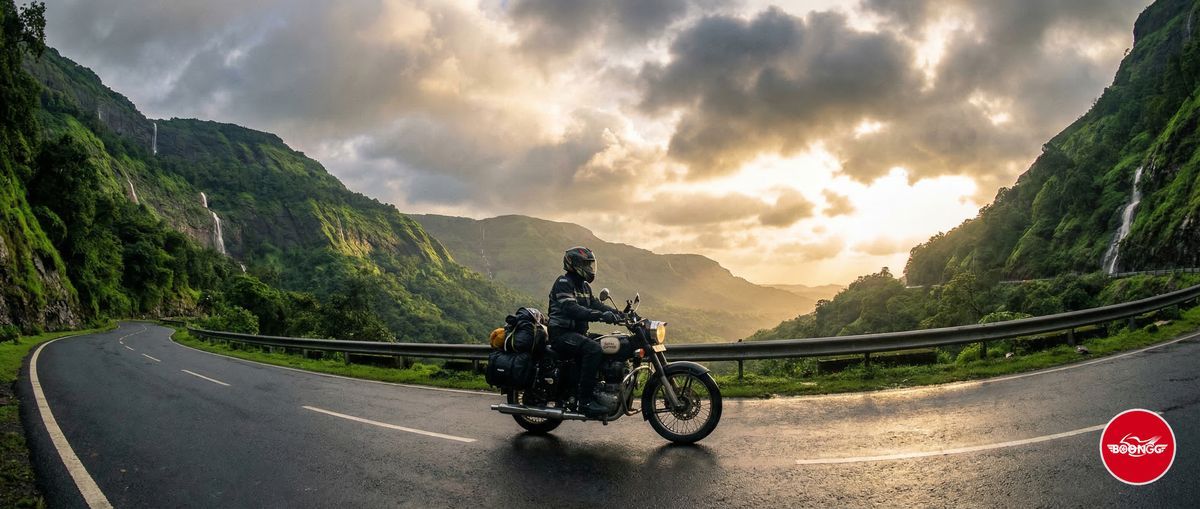 Rider on a motorcycle cruising through a scenic Western Ghats ghat road with lush green mountains on both sides near Pune