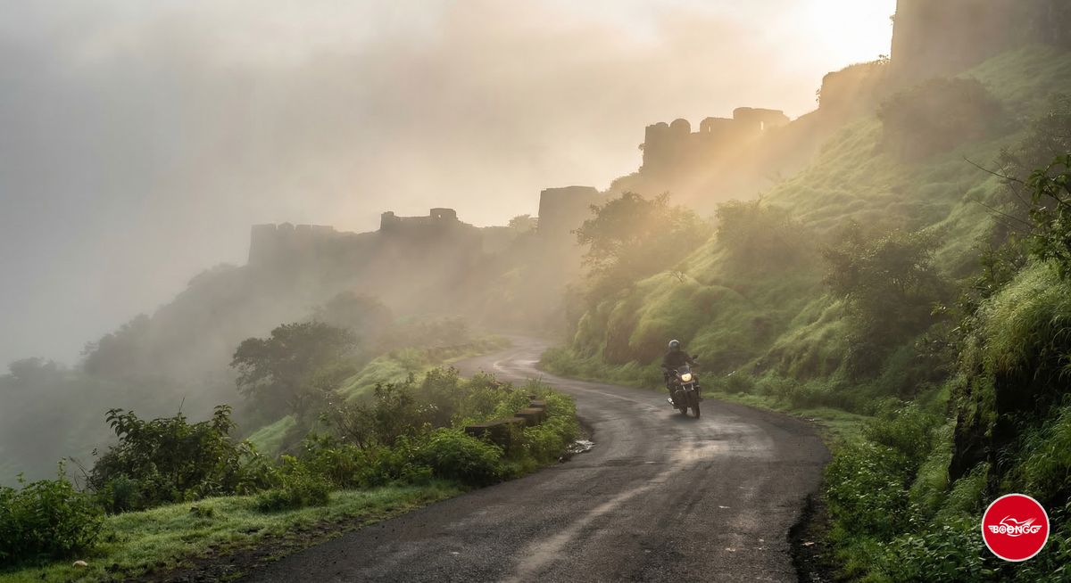 Sinhagad Fort road with morning mist and winding uphill path through green hills near Pune