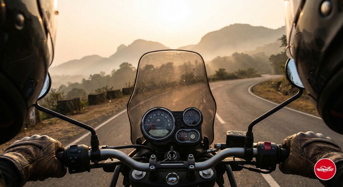Close-up of motorcycle handlebars and dashboard with an open sunrise road ahead through Western Ghats